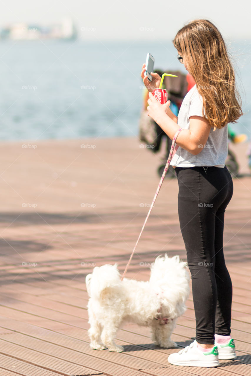 Young Girl With Her Dog Using Mobile Phone Outside