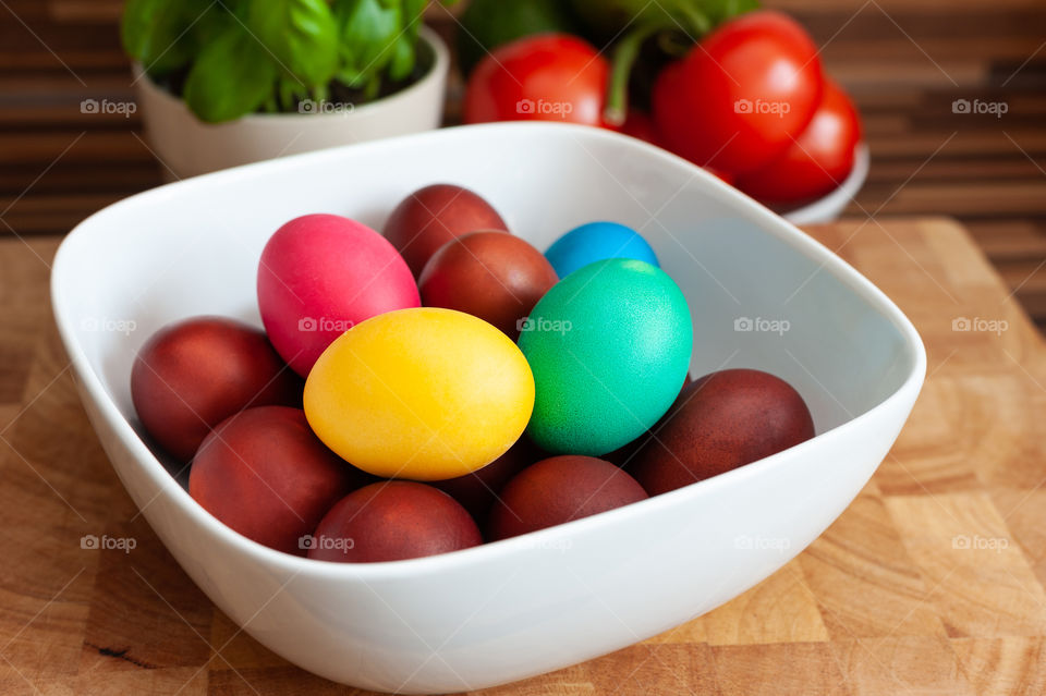 Colorful eggs in white bowl.