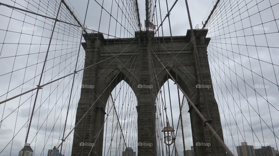 A view of the top portion of the Brooklyn Bridge on an overcast day.