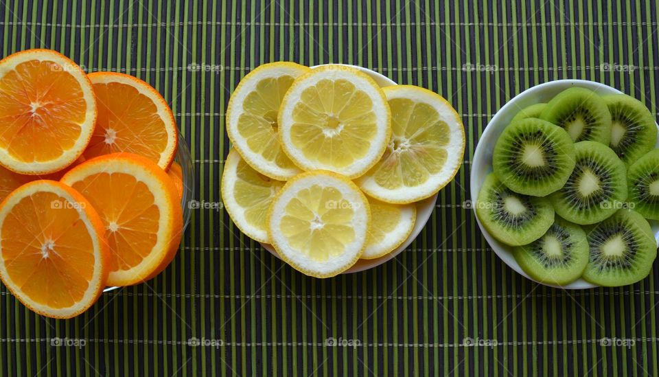 citrus fruits and kiwi sliced on a plate green table top view background