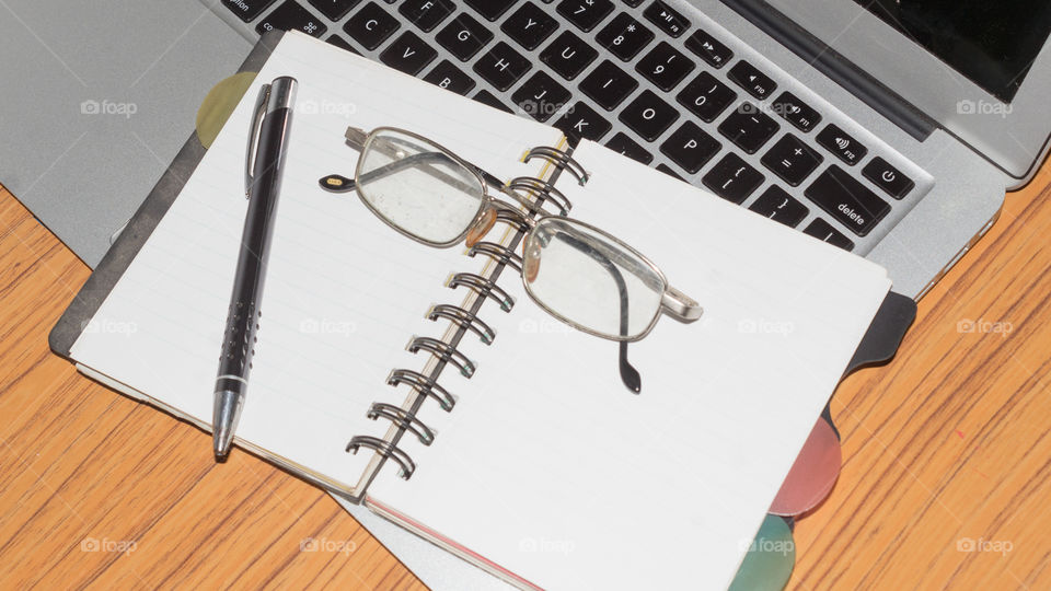 Desk with open notebook, pen, eye glasses, placed one another on office table. Top view with copy space. Business still life concept with office stuff on table. Education, working or planning concept