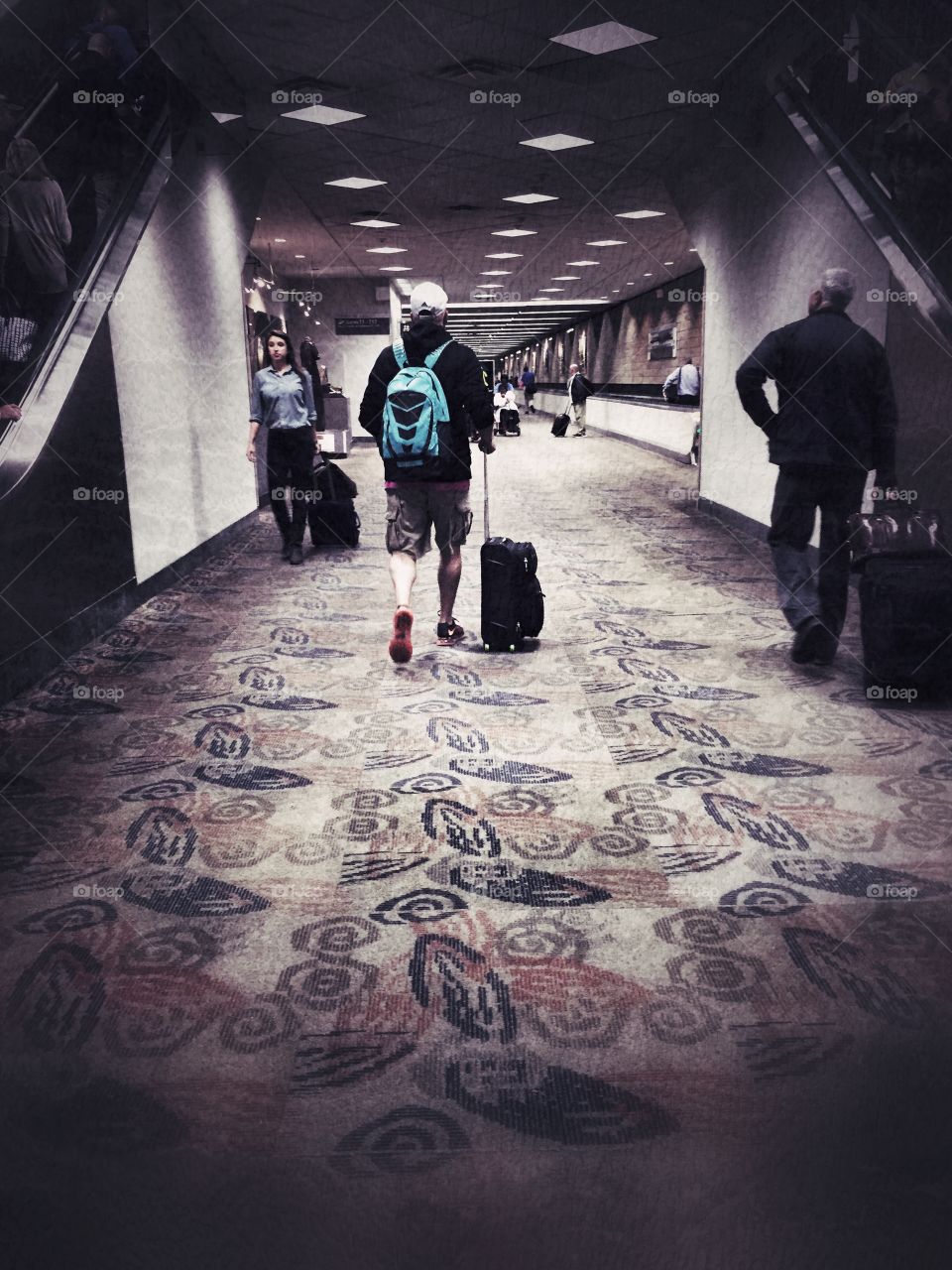 Man walks with his suitcase in a airport hallway 