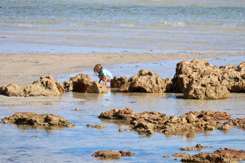 Little girl exploring the beach at low tide 