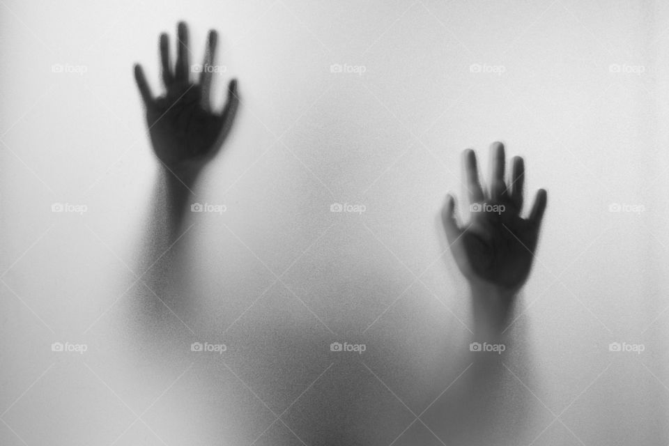 Shadow hands of the Man behind frosted glass.Blurry hand abstraction.Halloween background.Black and white picture