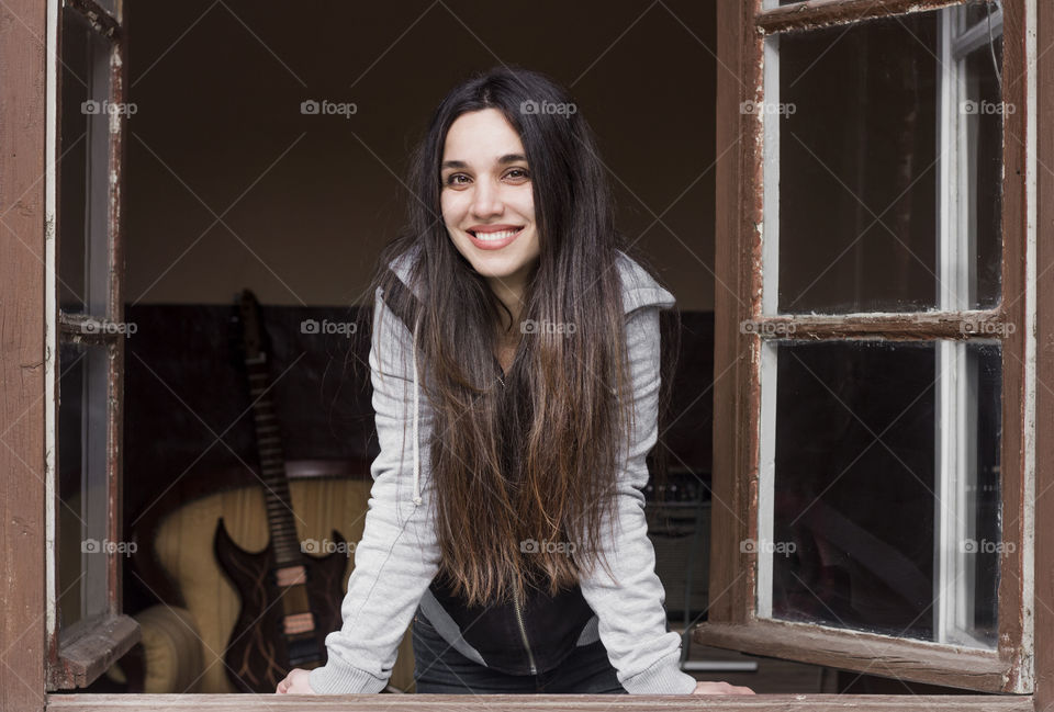 Beauitiful woman with long hair on the window, smiling