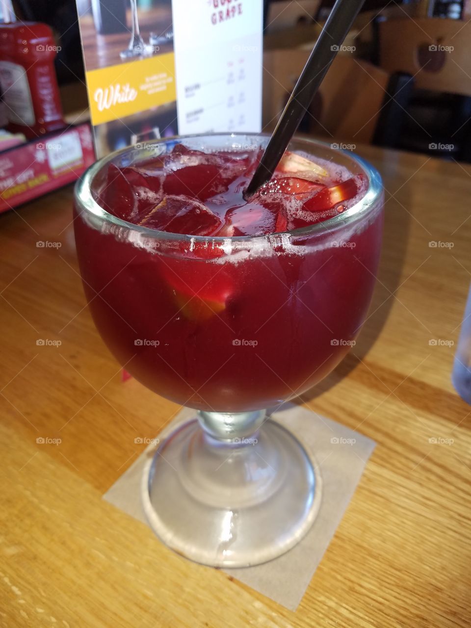 A refreshing alcoholic sangria drink in a familiar restaurant. Red and absolutely delicious.