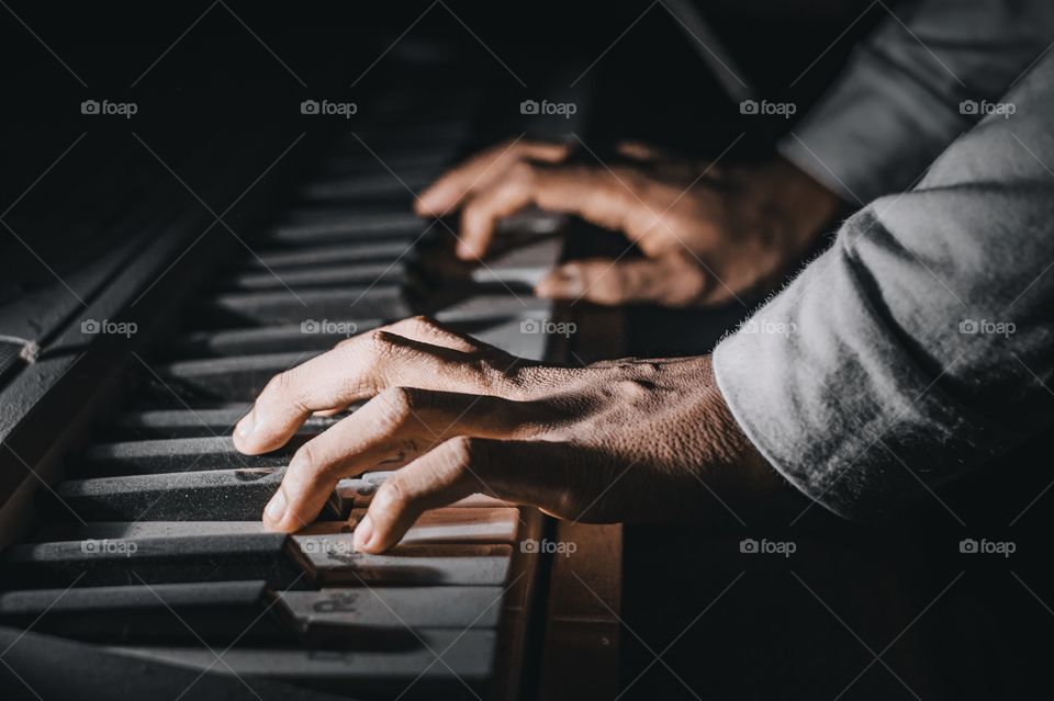 Close-up of a hand playing the piano in the dark