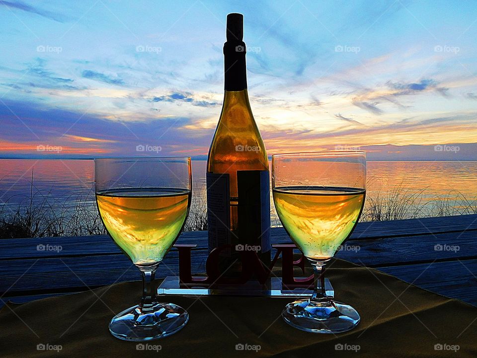 Romance and wine at the beach over a spectacular and colorful sunset. Oh how sweet it is to just stare at the sunset as it descends below the horizon and sip on a glass of wine