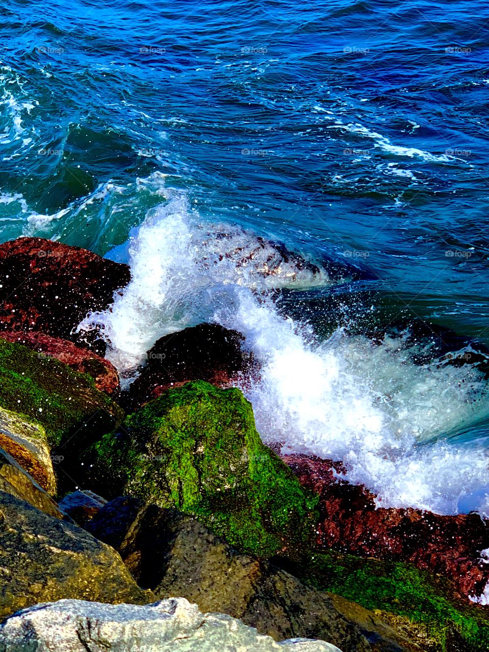 blue waves crashing against colorful rocks