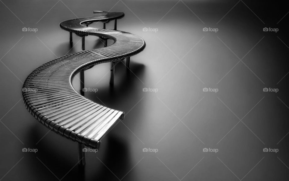 Monochrome photo of a bench illuminated on grey background