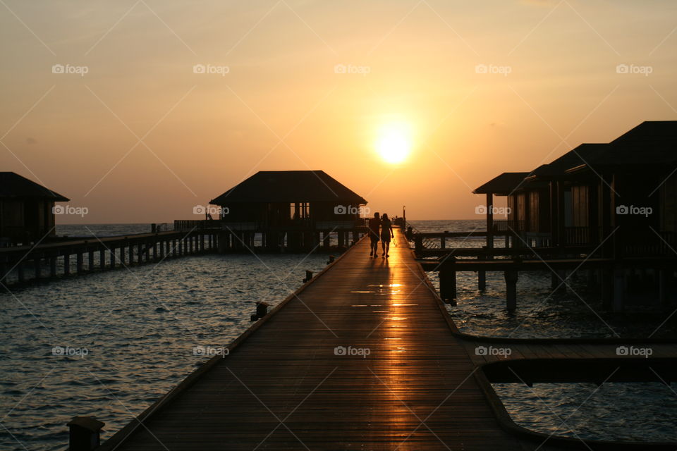Couple walking on pier during sunset