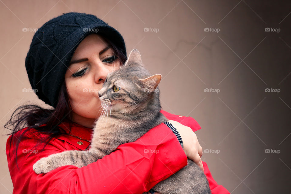 A woman in red holding and kissing cat