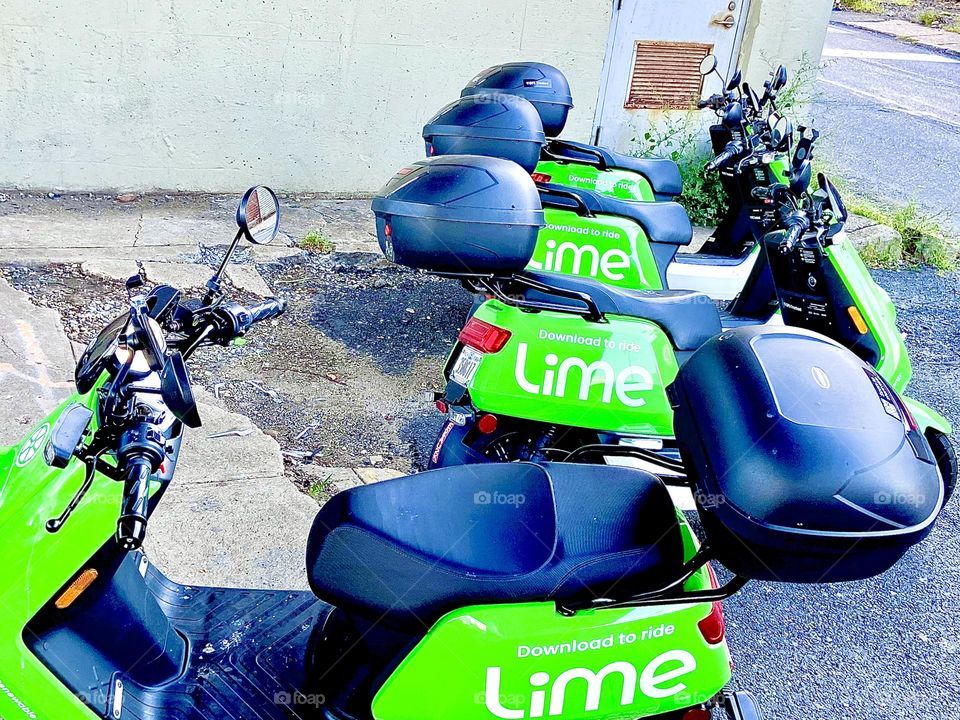 Three parked LIME electro scooters all lined up like „ducks in a row“ in the parking lot underneath the Pulaski Bridge in Long Island City, Queens, NY. 2021. Hypnotic Productions