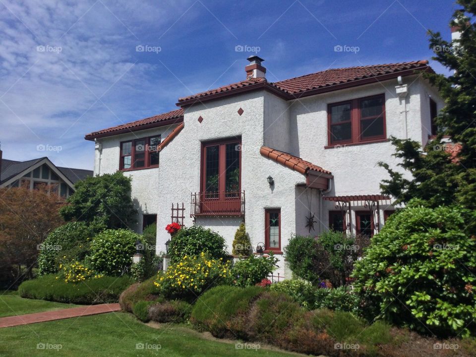 A unique stucco home with a red clay roof 