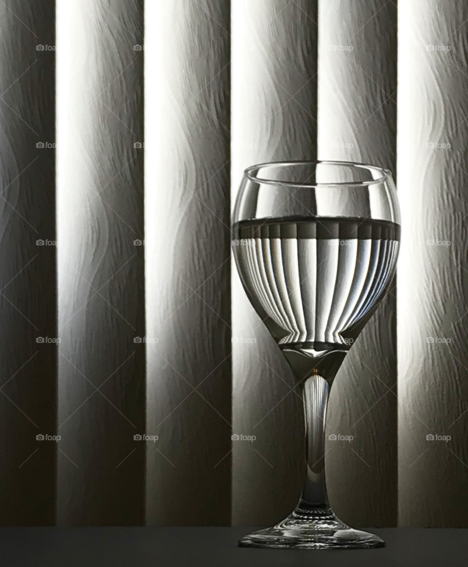 Wine glass with blinds reflecting into the glass