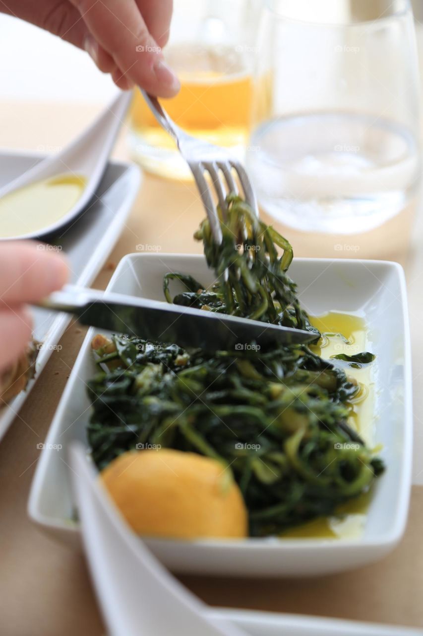 Person eating green vegetable on a plate 