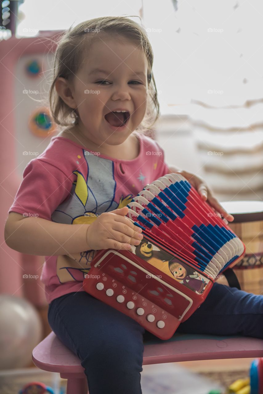 A little girl playing with toy accordion