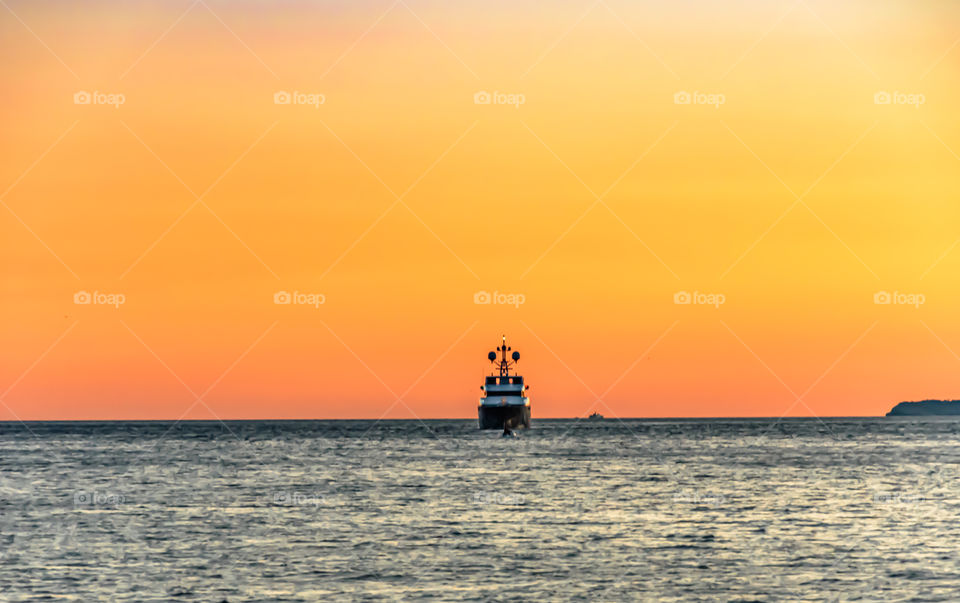 Ship sailing at sunset