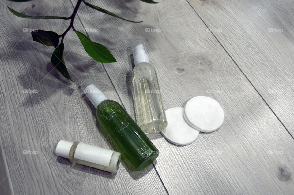 Jars with cream, shampoo and cosmetics on a background with green plants