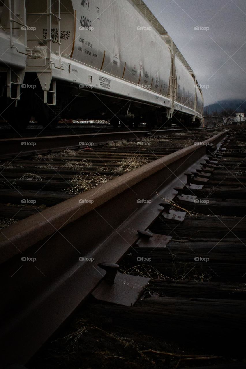 Long train tracks on a rainy day in New England. A white train to contrast the damp dark tracks and ground.