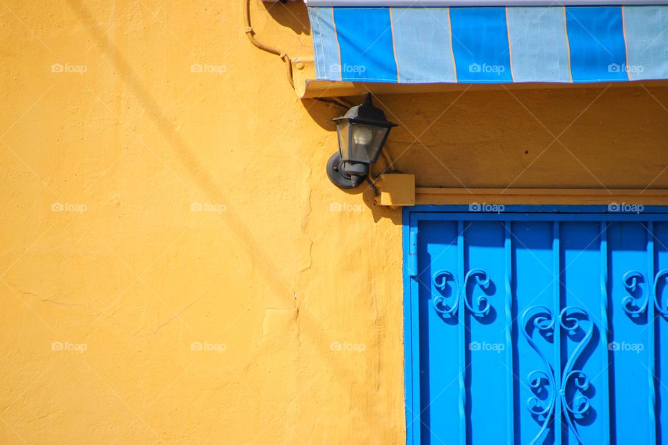 Close-up of a blue door and awning on an orange building