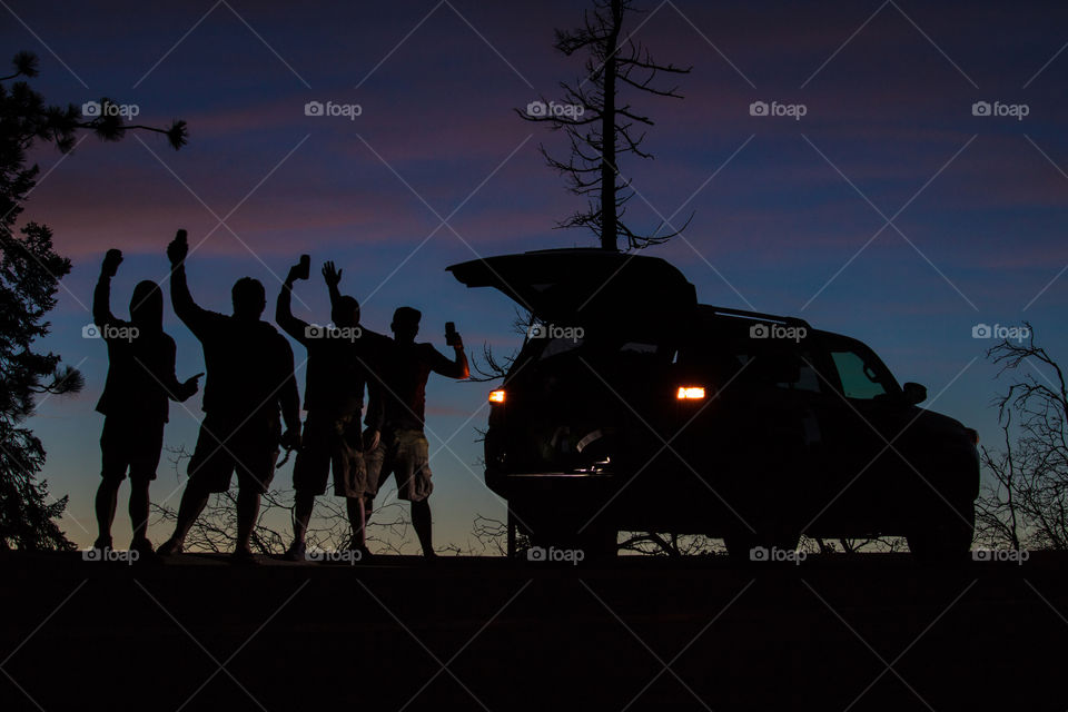 Group of friends posing on the side of the road with a sunset in the background