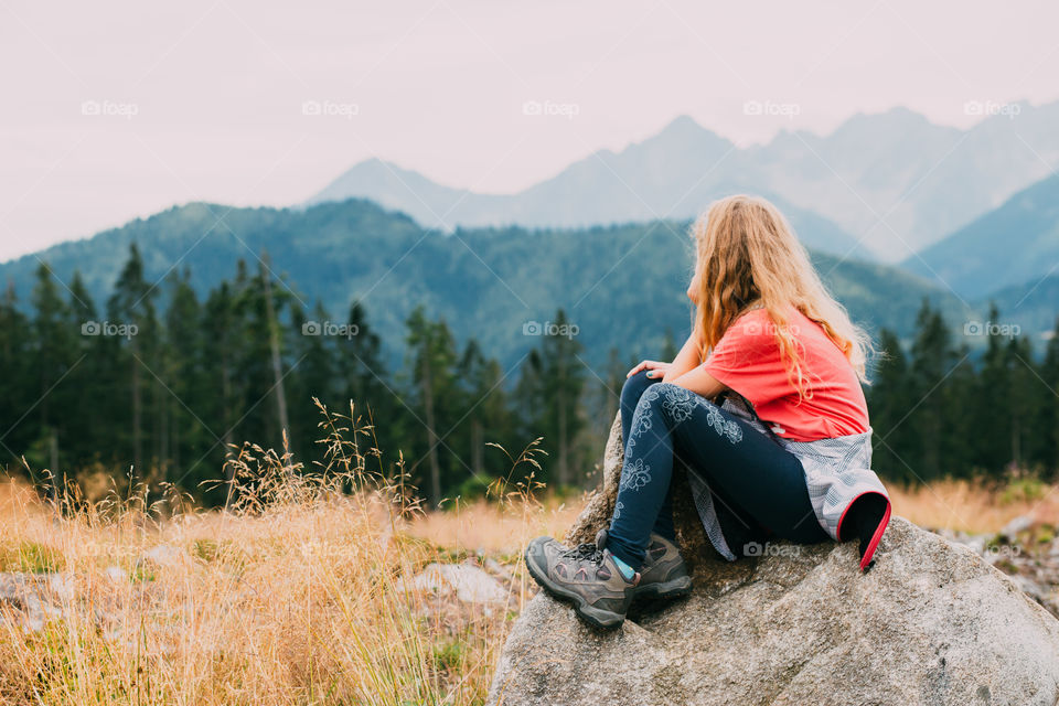 Back view of little girl jumping from stone to stone in the Tatra Mountains