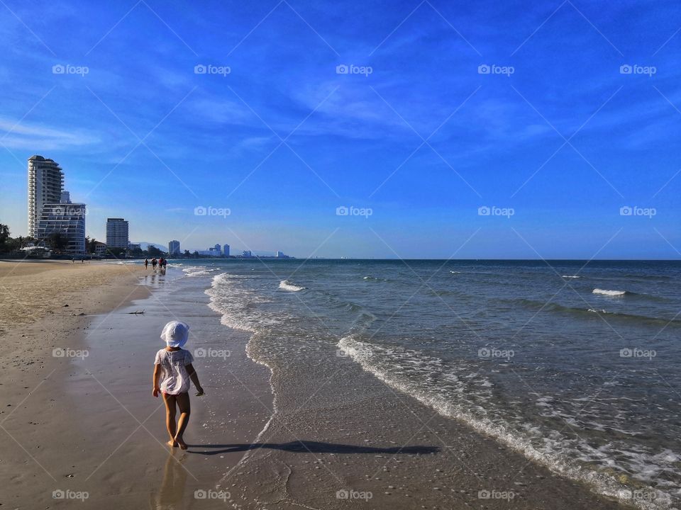 A small child walks along the beach