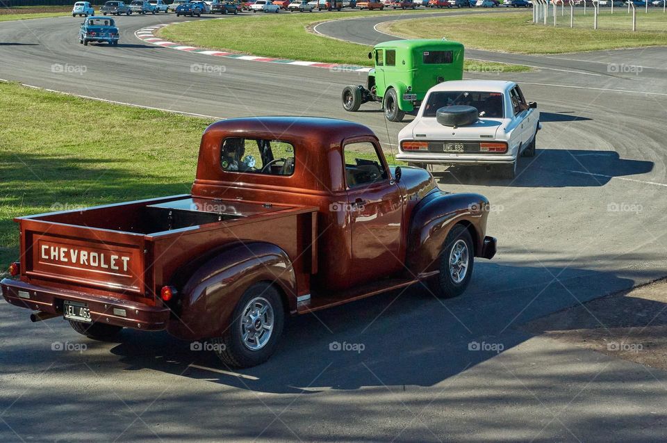 Collector cars entering a track for a parade lap.