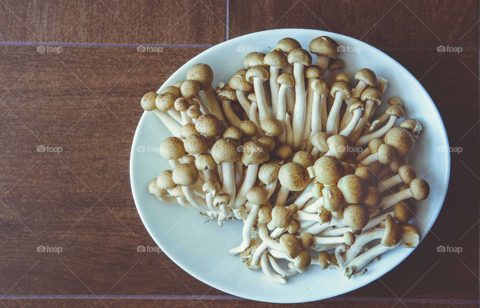 Mushrooms are in a white plate on wooden background