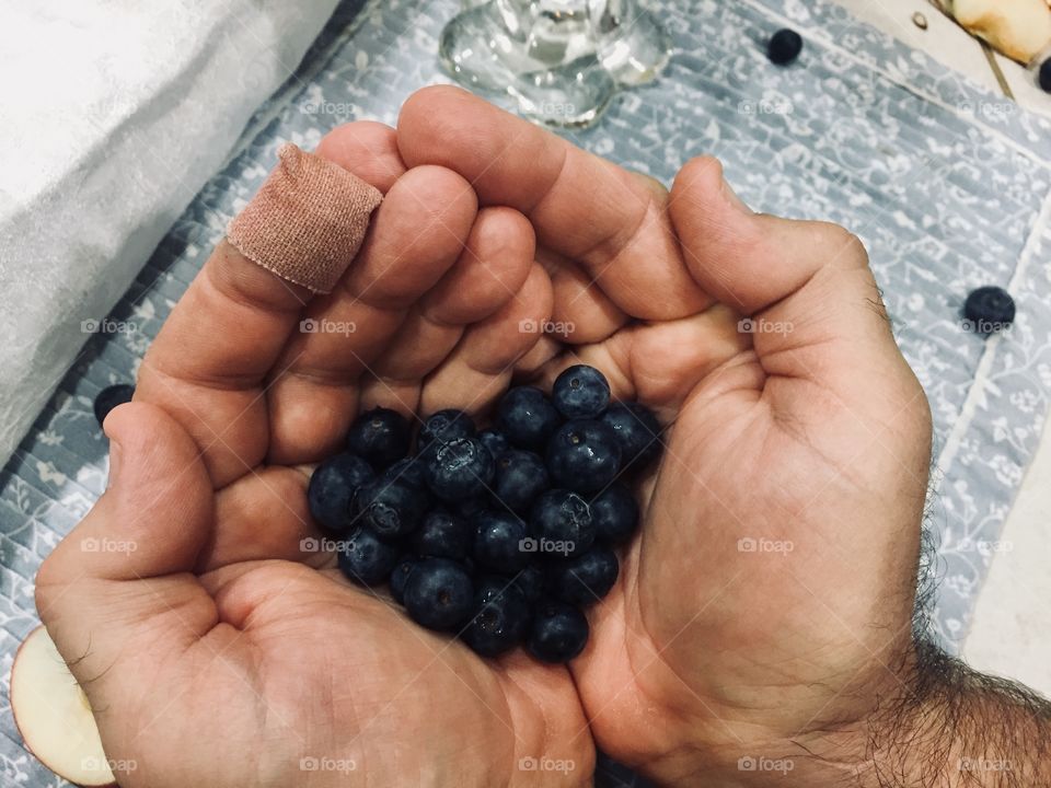 Freshly picked blueberries are held delicately in a hard working man’s hand. On his left hand is a bandage from a deep scrape he got while picking the berries, but the heart shape indicates that the cost was well worth the reward. 