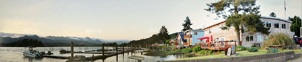 A panorama of the marina in Wheeler Oregon. the first building is the new salmonberry saloon, a Pacific Northwest original.  The ohoto shows the bay, boats and local buildings.