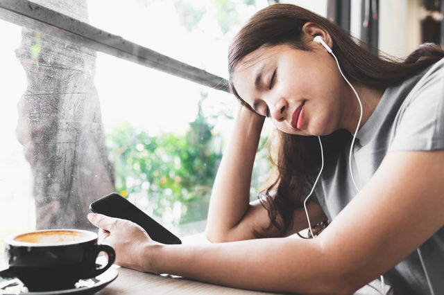 Asian woman feel relaxed, listening to music in the coffee shop