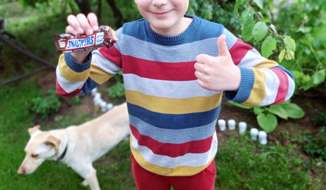 smiling boy holds a snickers