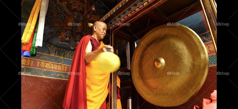 A buddhist monk hitting gong in a monastery near by boudha stupa