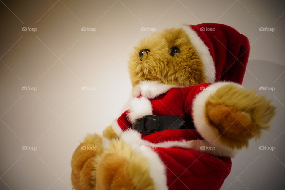 The side of teddy bear wearing in Santa costume.-Warm image.