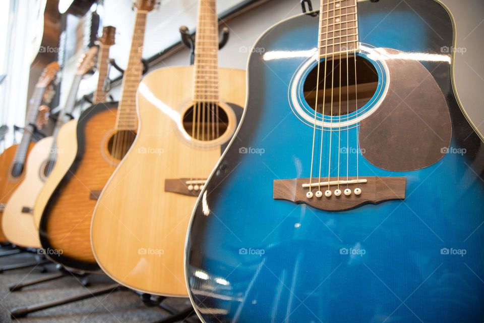 Low angle view of Guitars on sale. Stack of musical instruments . Blue and an yellow guitars .