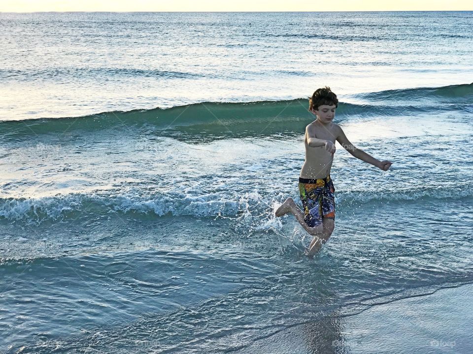 Boy playing in the ocean.