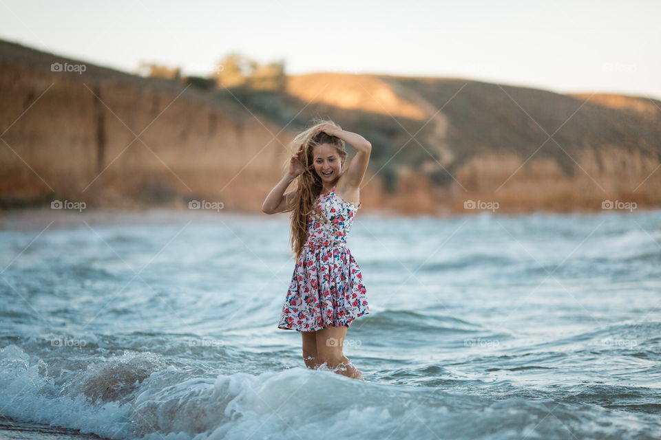 Portrait of beautiful young woman near the sea at sunset