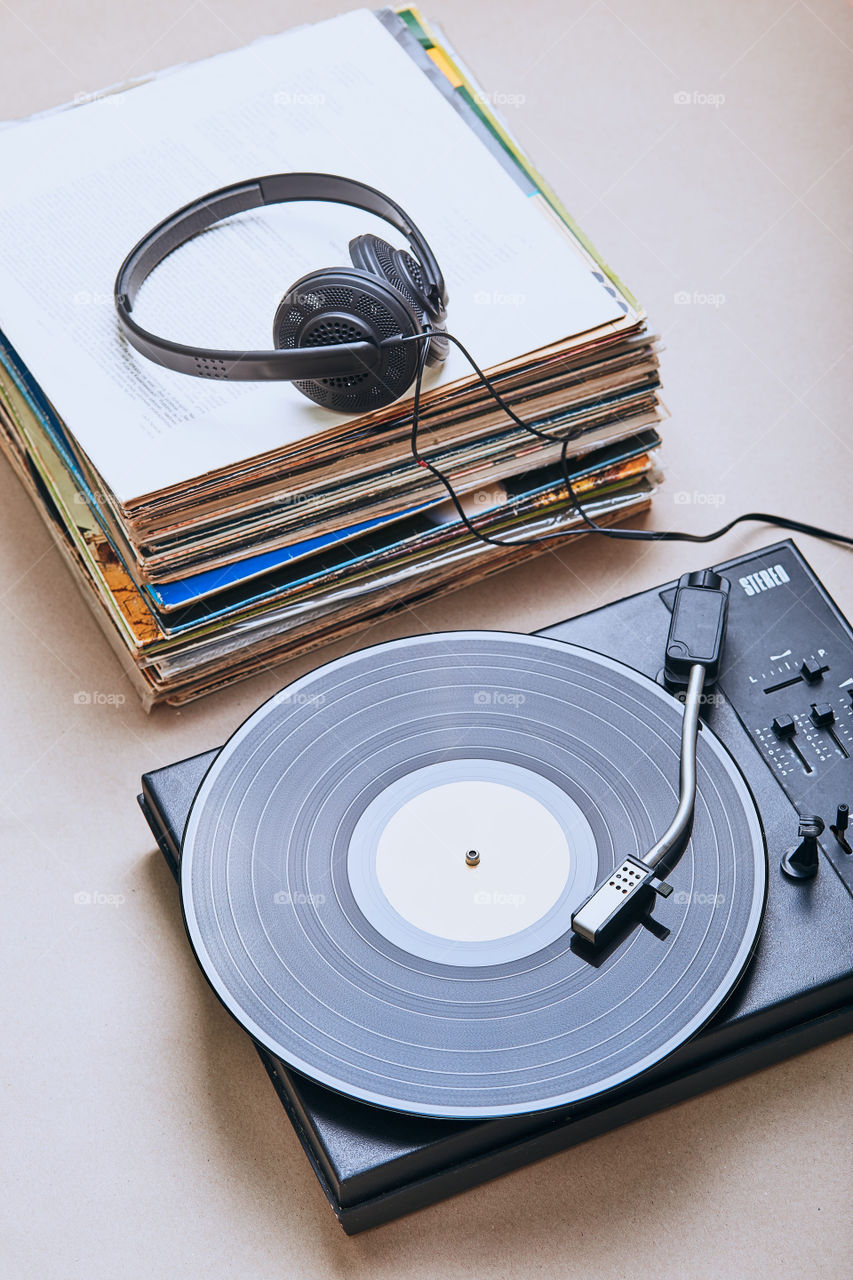 Stack of black vinyl records, turntable vinyl player and headphones. Classic stereo set. Candid people, real moments, authentic situations