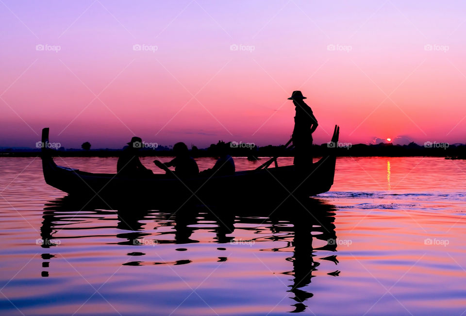 Silhouette of people traveling in boat during sunset