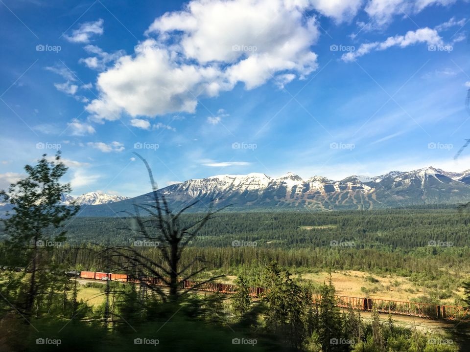Train winding through valley with Canadian Rocky Mountain backdrop
