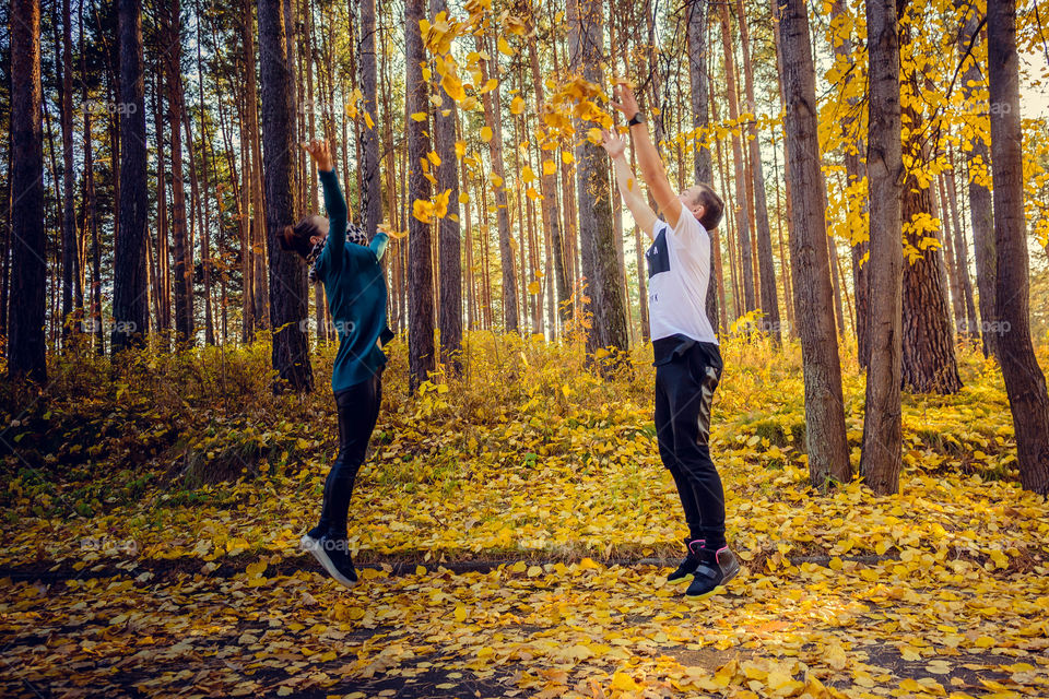 Man and woman jumping in autumn forest