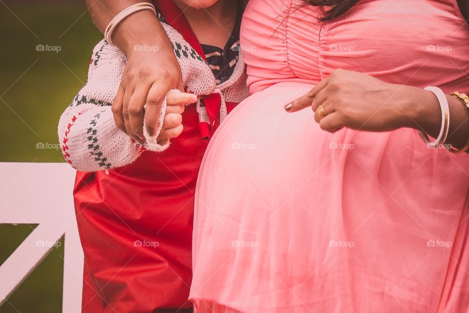 A pregnant woman playing with a kid showing her womb.