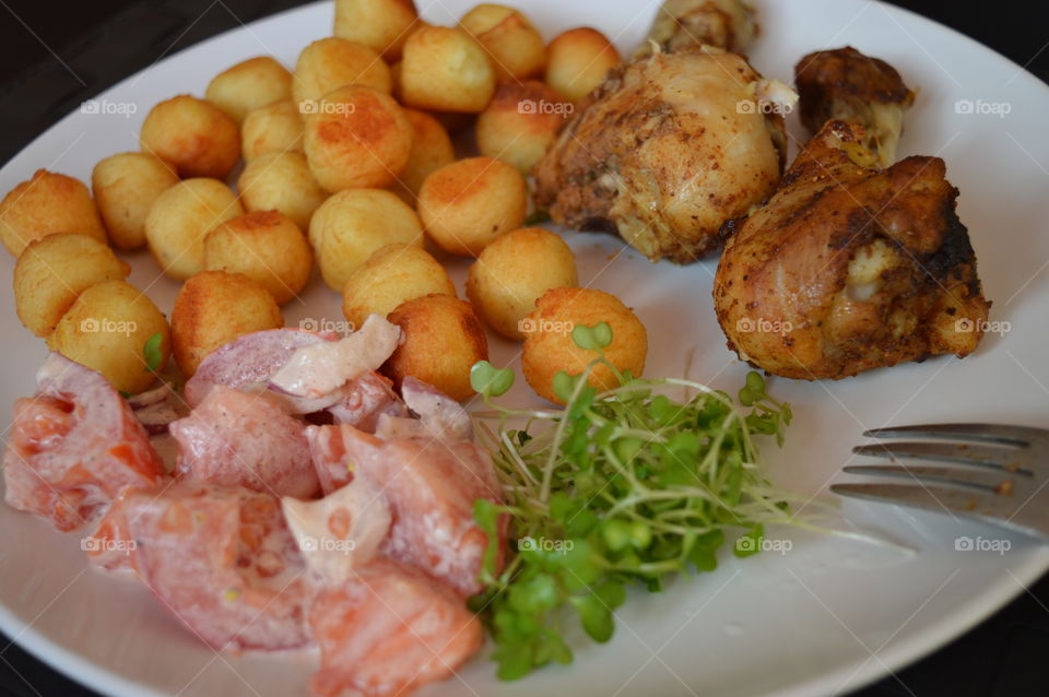 A delicious dish. Chicken legs with baked potato balls and salad with fresh cress