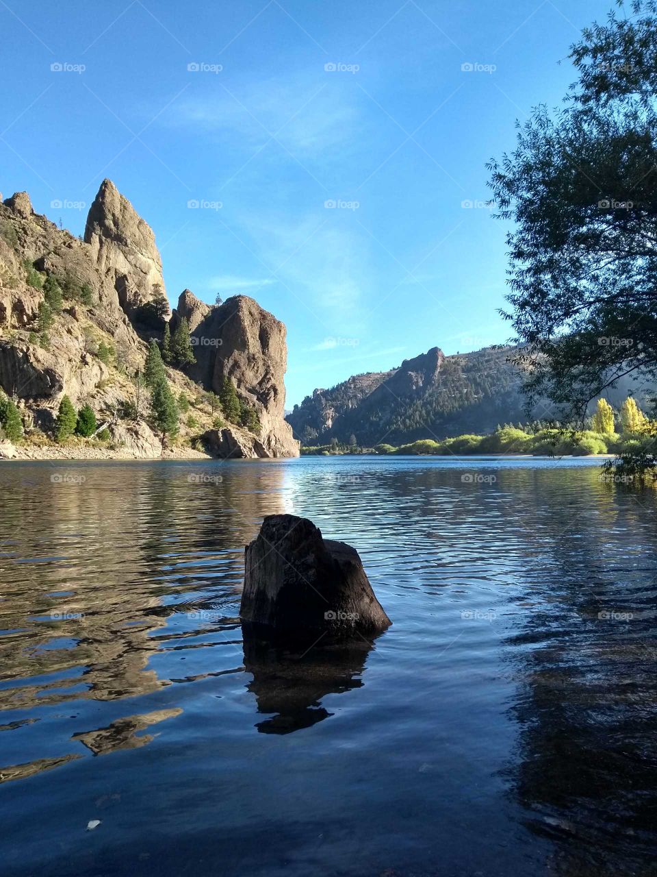 Piedra en un lago cristalino con montañas detrás en un hermoso día de verano