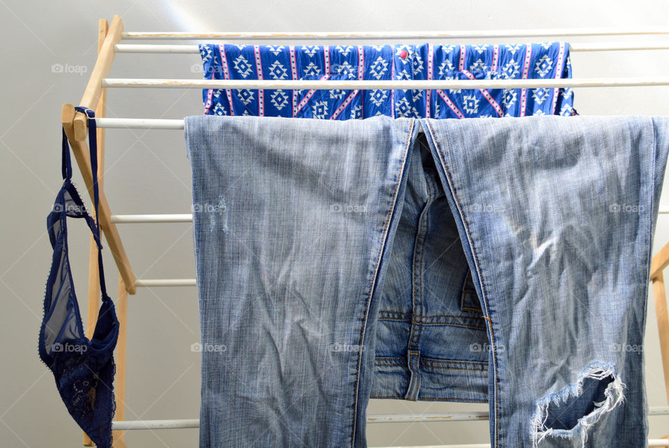 Shirt, jeans and bra hanging on a clothes rack to dry