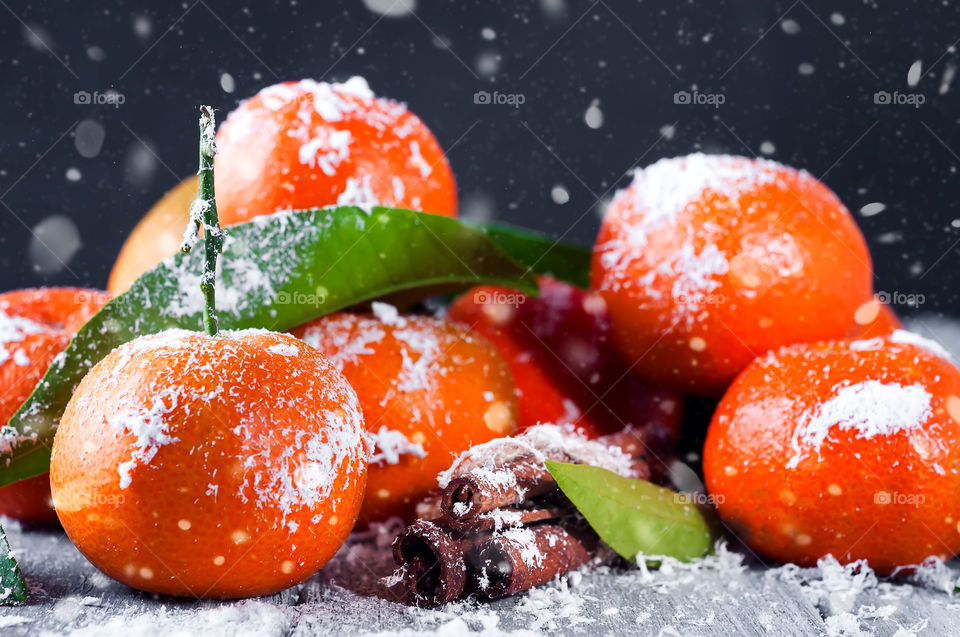 Delicious tangerines with snow on a dark wooden background