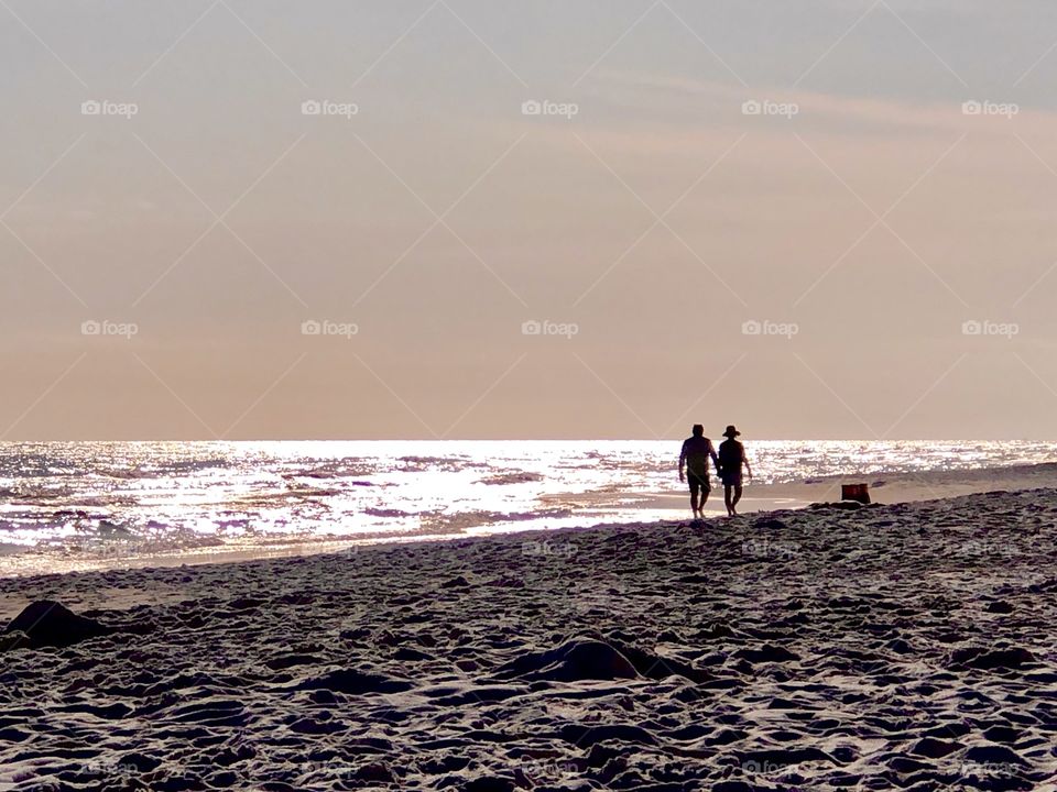Couple walking along beach in late afternoon light
