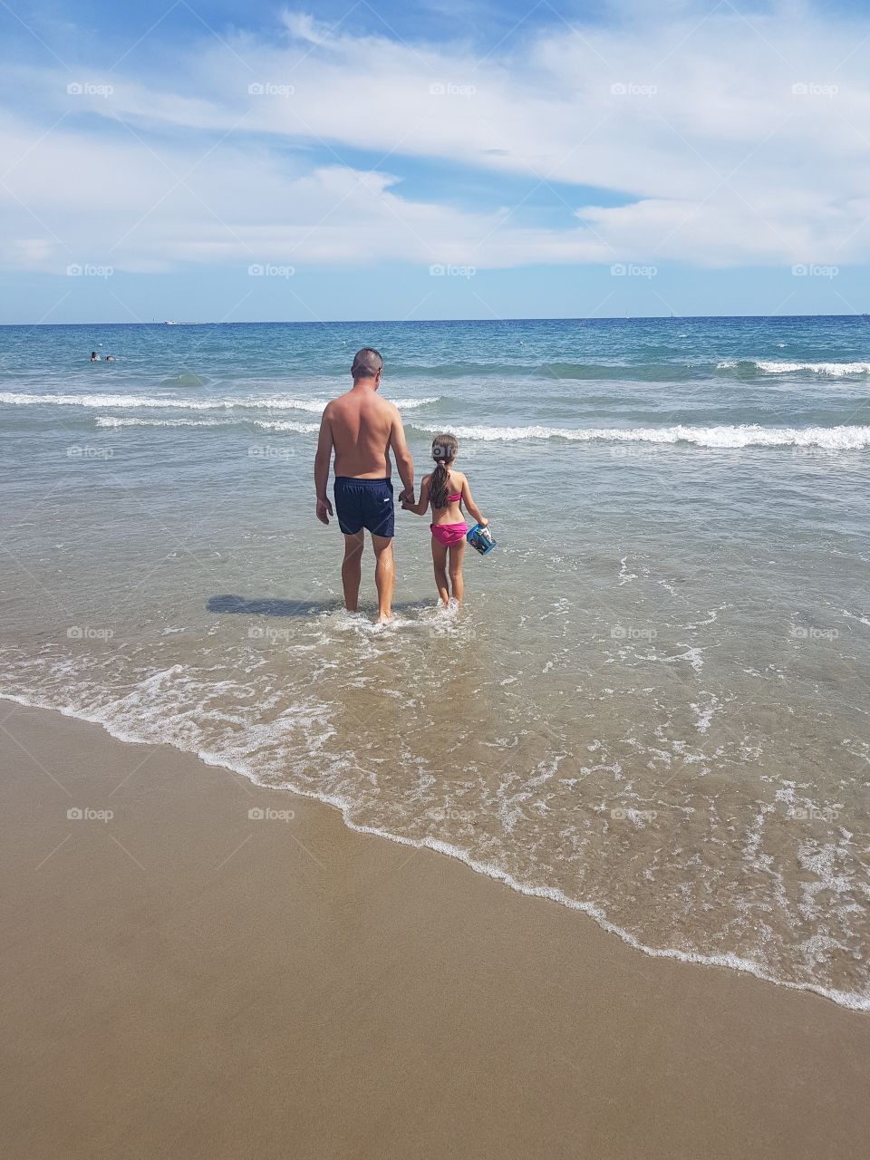 Little girl with her dad walking on the shore in italian Riviera